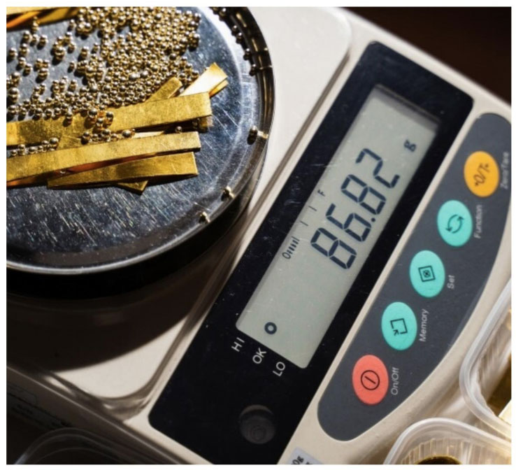 Digital gold scale measuring a small gold ring on a stainless steel platform.