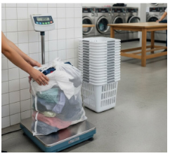 Person weighing a large bag of laundry on a digital floor scale in a laundromat.