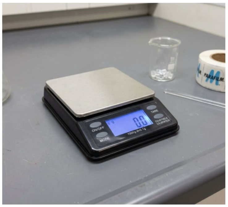US Balance scale on a workbench weighing small parts with a clear digital readout.
